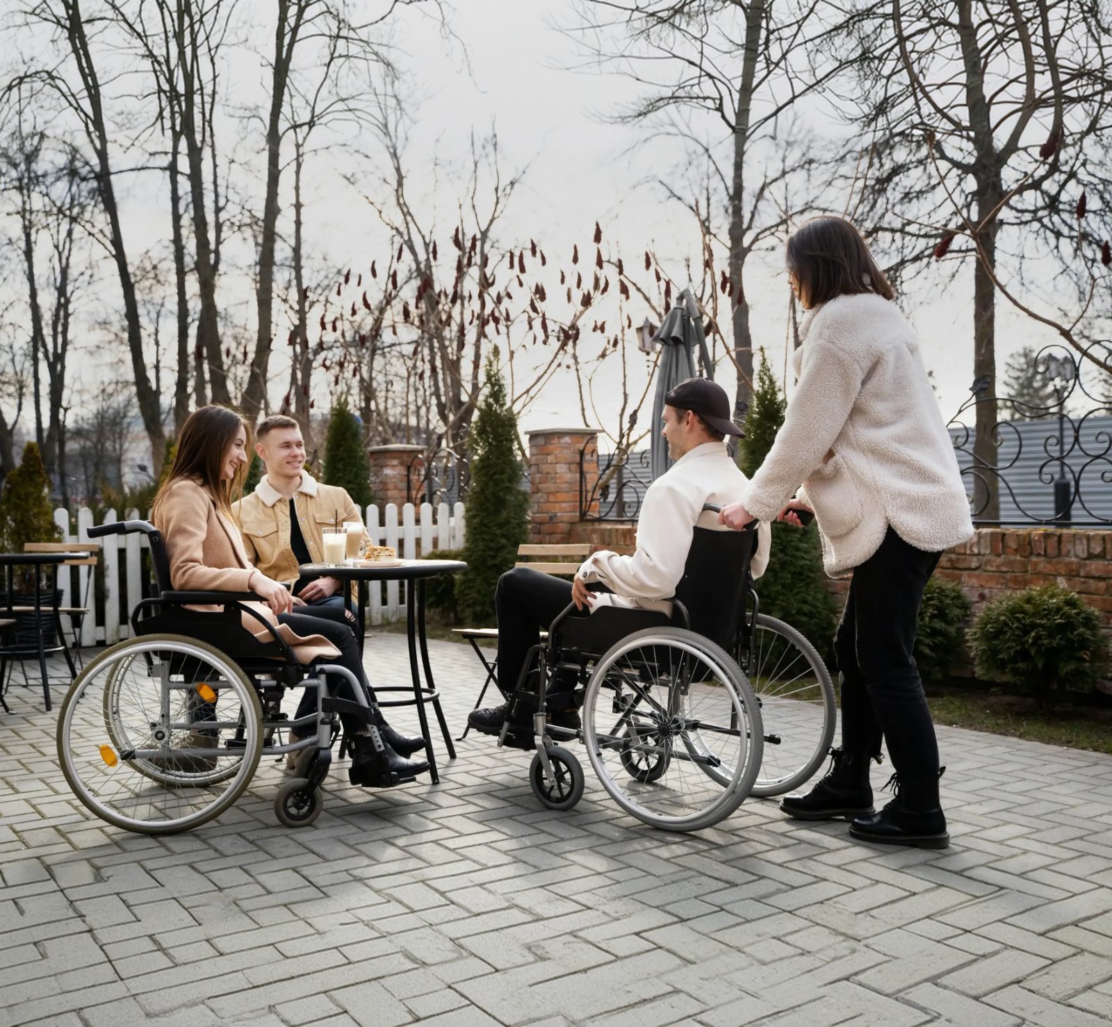 Support worker assisting a man in a wheelchair outdoors with friends