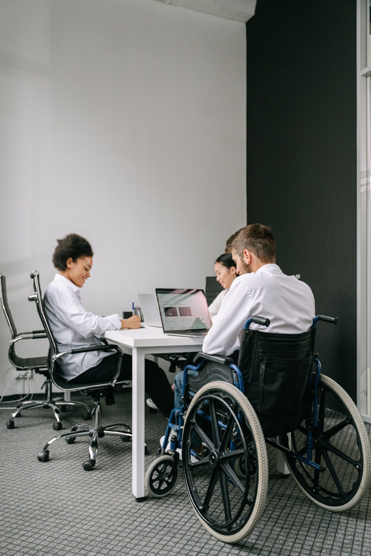 Young people working together at a desk, one in a wheelchair