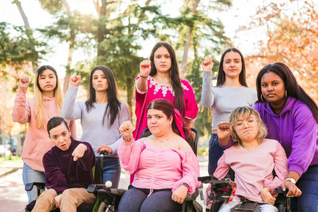 Group of women, some in wheelchairs, raising their fists together